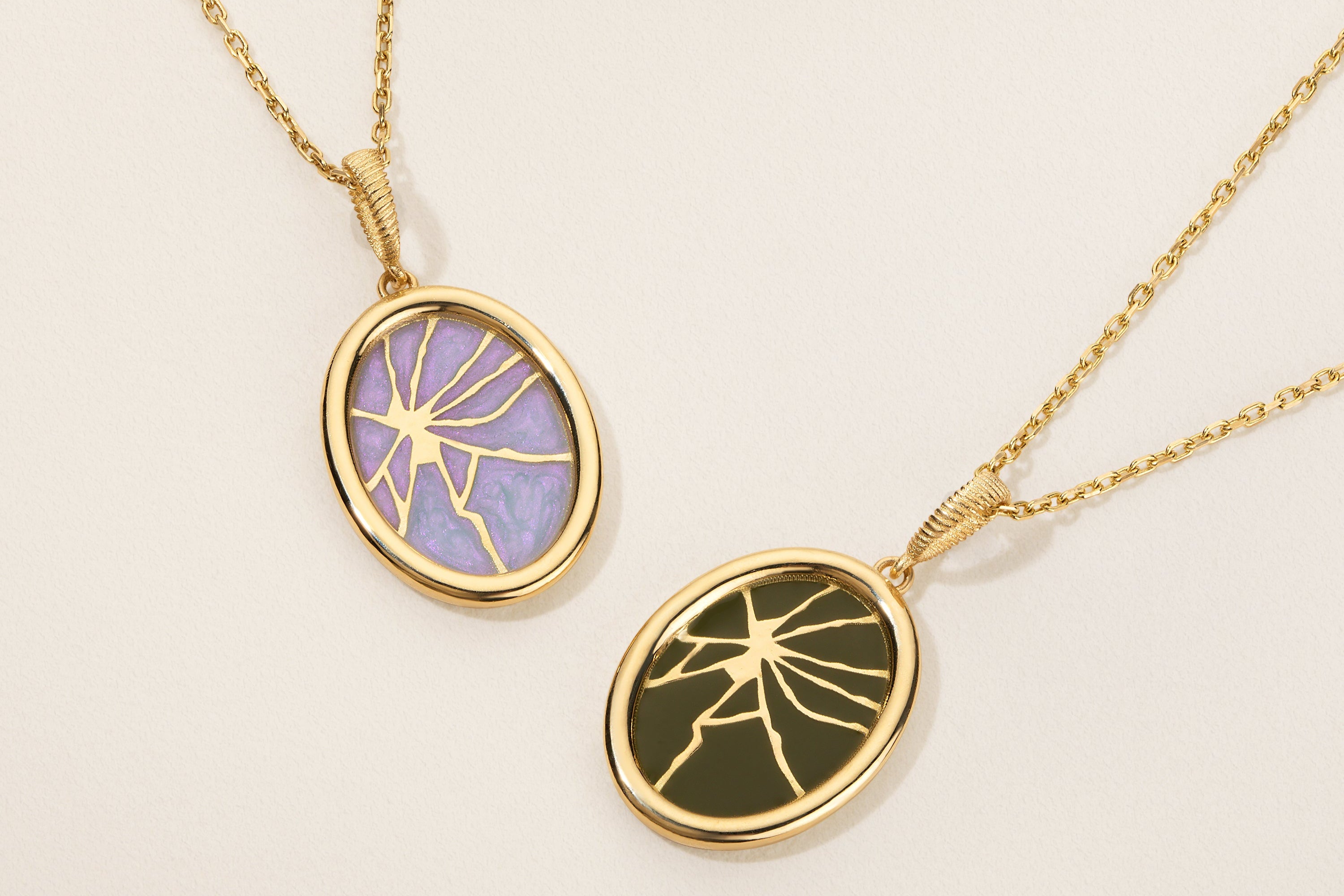 Two gold necklaces with oval pendants on a beige background