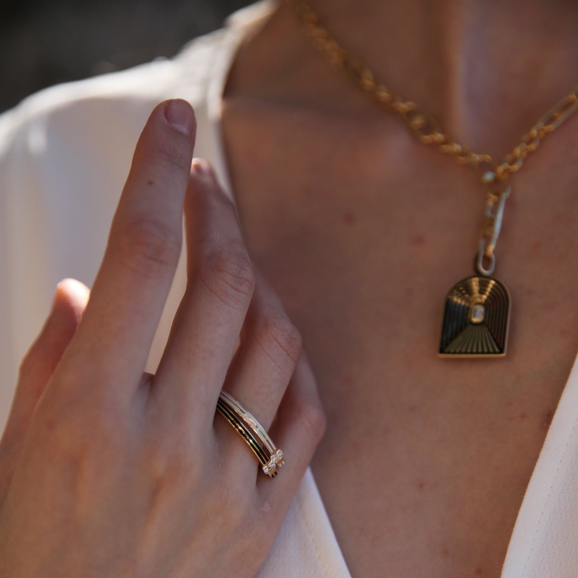 Close-up of a hand with a ring and a necklace with a pendant on a blurred background
