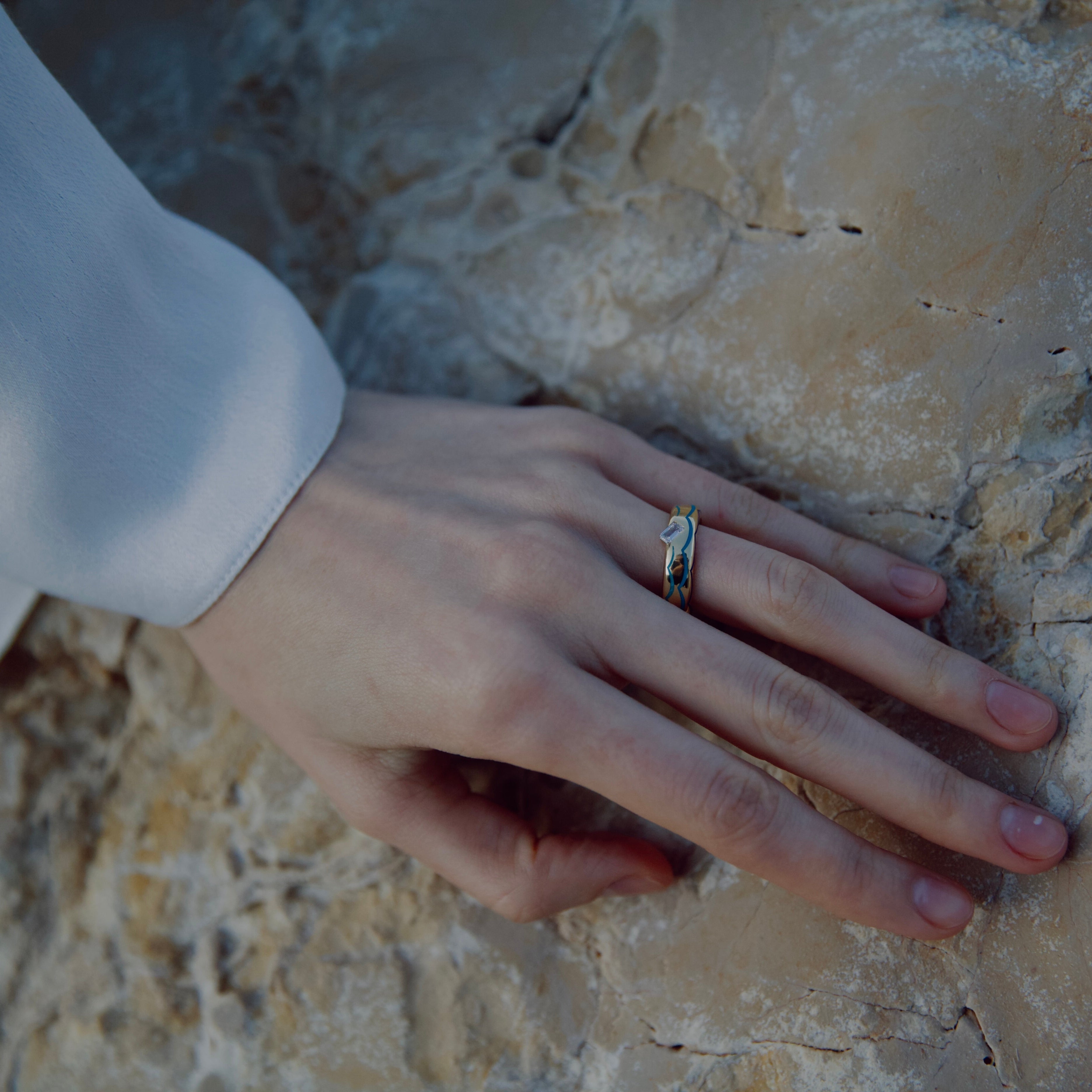 Hand with a ring on a textured stone surface