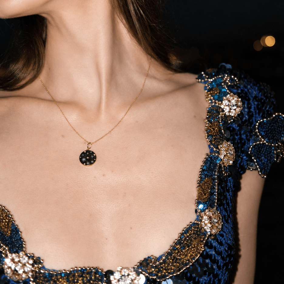 Close-up of a person wearing a blue embroidered dress with gold details against a dark background.