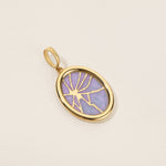 Gold pendant with a purple stone on a beige background