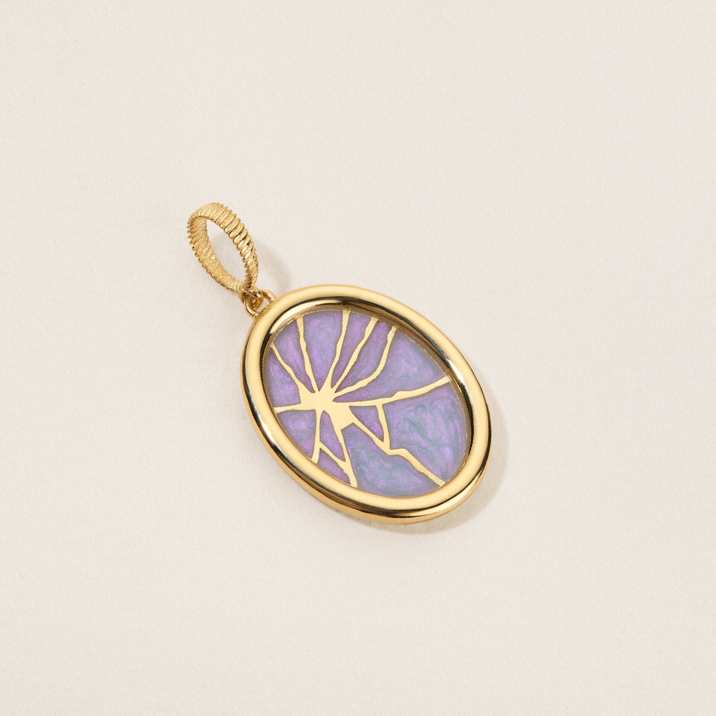 Gold pendant with a purple stone on a beige background