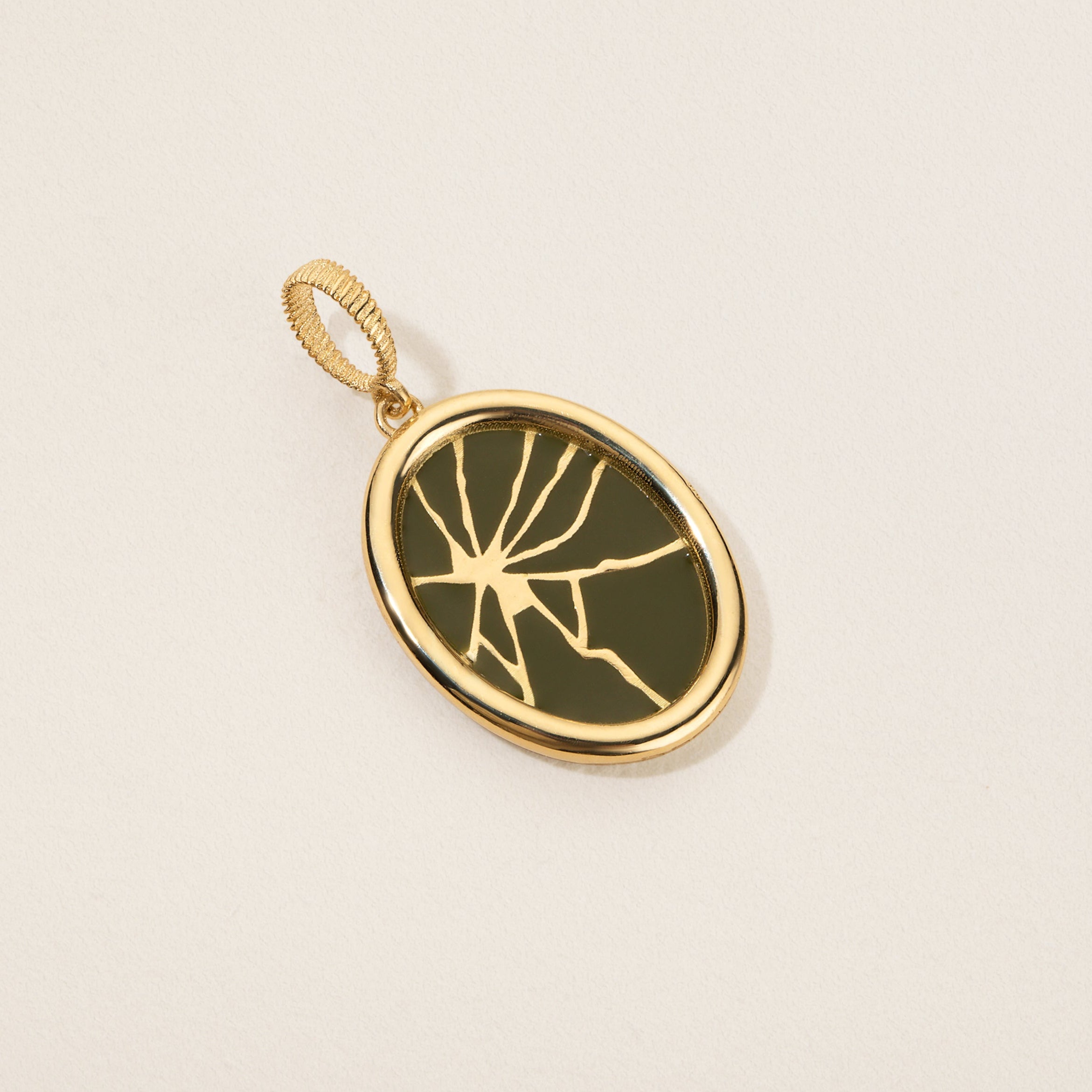 Gold pendant with a green stone on a beige background