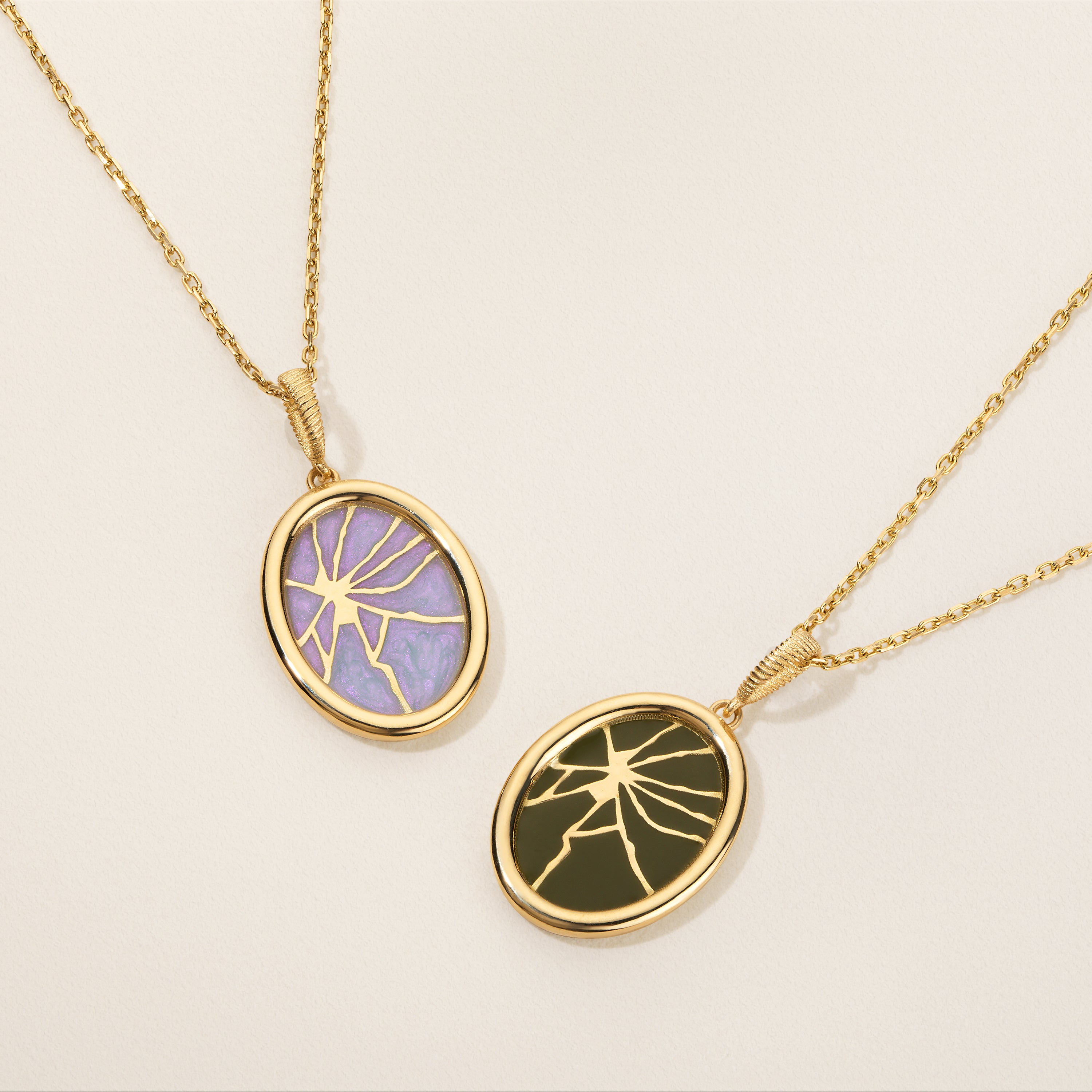 Two gold necklaces with oval pendants on a beige background